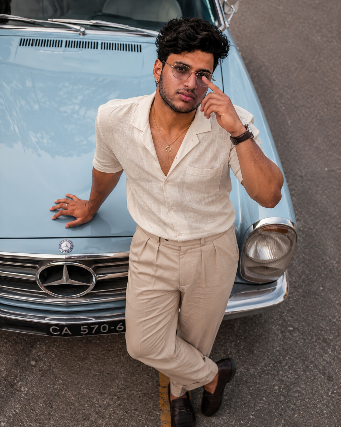 High-Angle Vintage Car Fashion Portrait – Man in Ivory Linen Outfit Posing on a Classic Blue Sedan